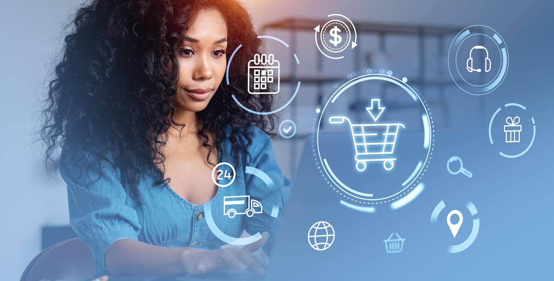 African woman using laptop, glowing hologram shopping cart and e-commerce icons